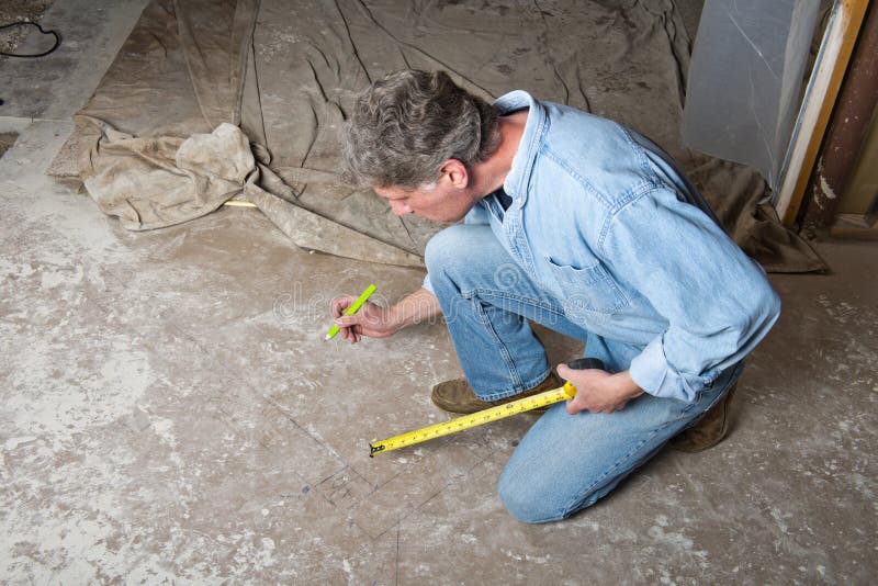 A man who is a contractor doing house and home remodeling work is measuring out walls and doors in a basement remodel. His tools here are a tape measure and pencil. The male construction worker is working on a basement project. Home improvement is a big industry. A man who is a contractor doing house and home remodeling work is measuring out walls and doors in a basement remodel. His tools here are a tape measure and pencil. The male construction worker is working on a basement project. Home improvement is a big industry.