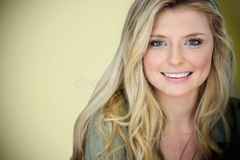 Close up portrait of smiling young blonde woman against light green background. Close up portrait of smiling young blonde woman against light green background