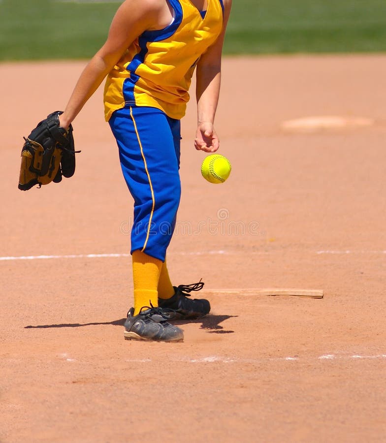 Fastpitch softball pitcher releasing softball towards the hitter at the plate. Fastpitch softball pitcher releasing softball towards the hitter at the plate