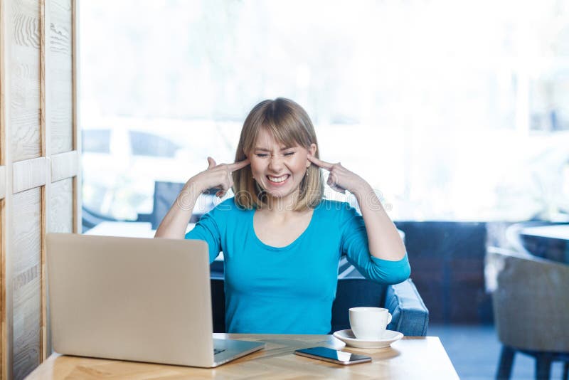 ¡No quiera oír! El retrato del freelancer interesante atractivo de la chica joven en blusa azul se está sentando en café y está h imagenes de archivo ¡No quiera oír! El retrato del freelancer interesante atractivo de la chica joven en blusa azul se está sentando en café y está h imagenes de archivo