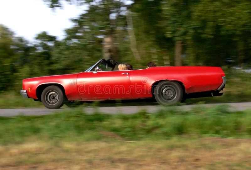 Three women enjoying the sun in their shabby red convertible while driving down a small country road. Three women enjoying the sun in their shabby red convertible while driving down a small country road