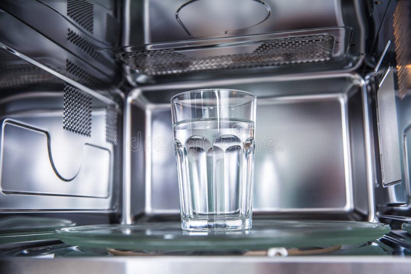 À l'intérieur de la vue de nouveau staniless propre, four à micro-ondes avec une tasse de l'eau pure photographie stock libre de droits À l'intérieur de la vue de nouveau staniless propre, four à micro-ondes avec une tasse de l'eau pure photographie stock libre de droits