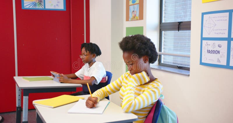 À l'école, les enfants qui étudient sur les bureaux écrivent dans le bloc-notes un en utilisant la tablette clips vidéos