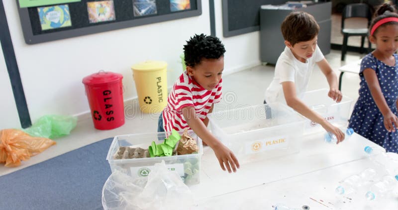 À l'école, les enfants trient les matières recyclables dans des bacs pour apprendre à gérer les déchets banque de vidéos