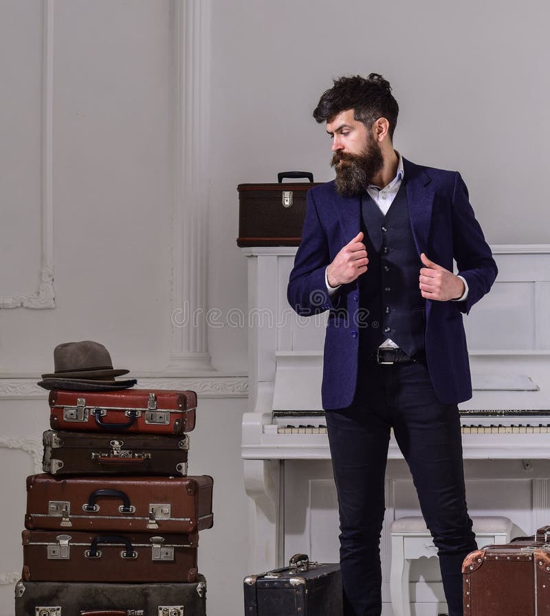 À moda macho na cara pensativa que está a pilha próxima da mala de viagem do vintage Homem, viajante com barba e bigode com fotos de stock royalty free À moda macho na cara pensativa que está a pilha próxima da mala de viagem do vintage Homem, viajante com barba e bigode com fotos de stock royalty free