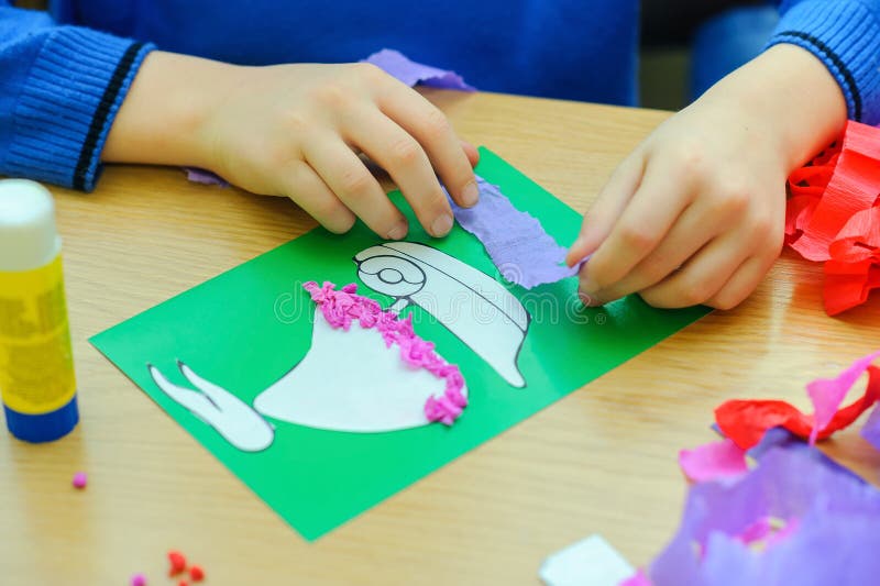 Сhild, Boy of school age, does hand-made articles on a school table, pastes paper strips, application on the sheet of paper. Сhild, Boy of school age, does hand-made articles on a school table, pastes paper strips, application on the sheet of paper