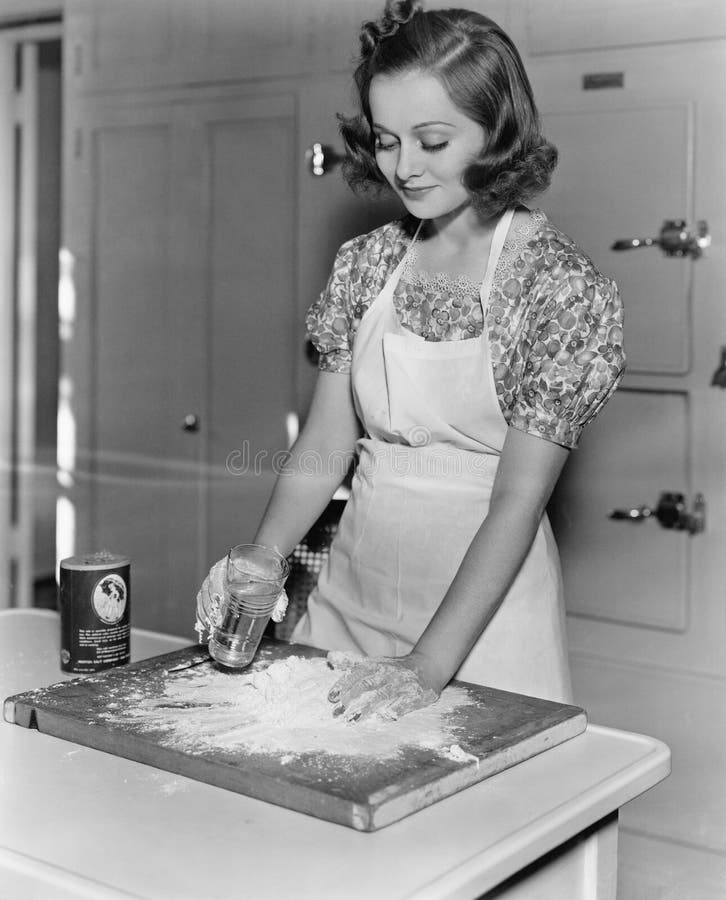 Young woman pouring water into flour (All persons depicted are no longer living and no estate exists. Supplier grants that there will be no model release issues.). Young woman pouring water into flour (All persons depicted are no longer living and no estate exists. Supplier grants that there will be no model release issues.)