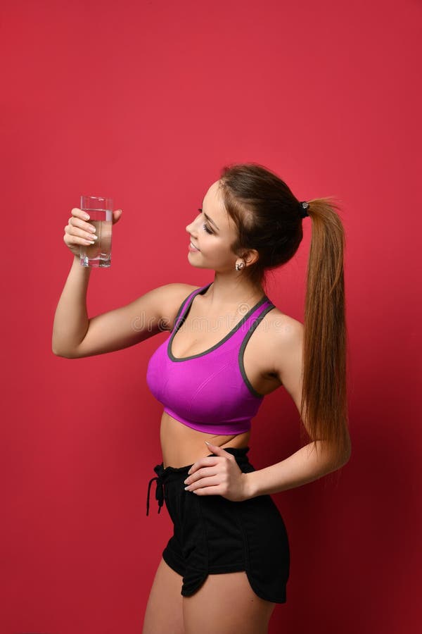 Água potável bonita da mulher do esporte do vidro no fundo cor-de-rosa imagens de stock royalty free Água potável bonita da mulher do esporte do vidro no fundo cor-de-rosa imagens de stock royalty free