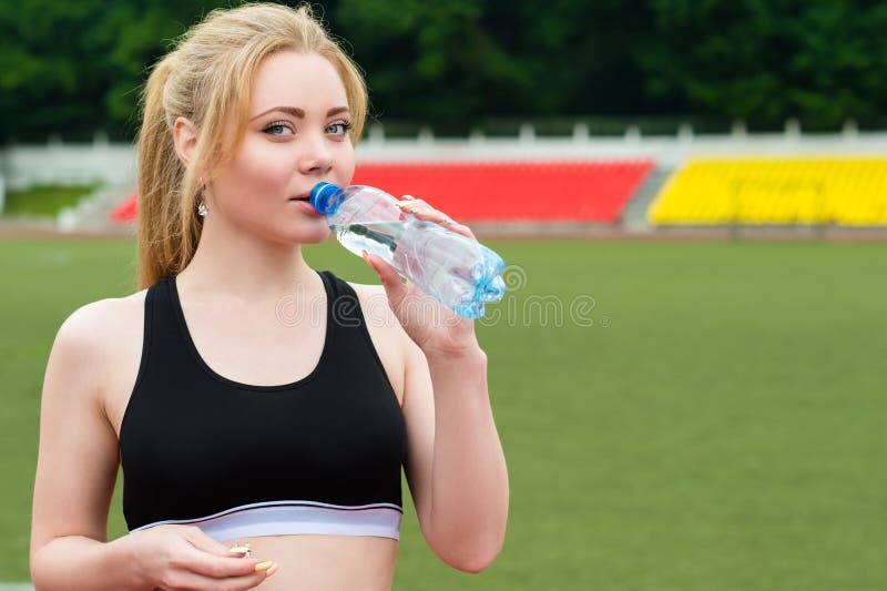 Água potável bonita da mulher dos esportes de uma garrafa fotografia de stock royalty free Água potável bonita da mulher dos esportes de uma garrafa fotografia de stock royalty free