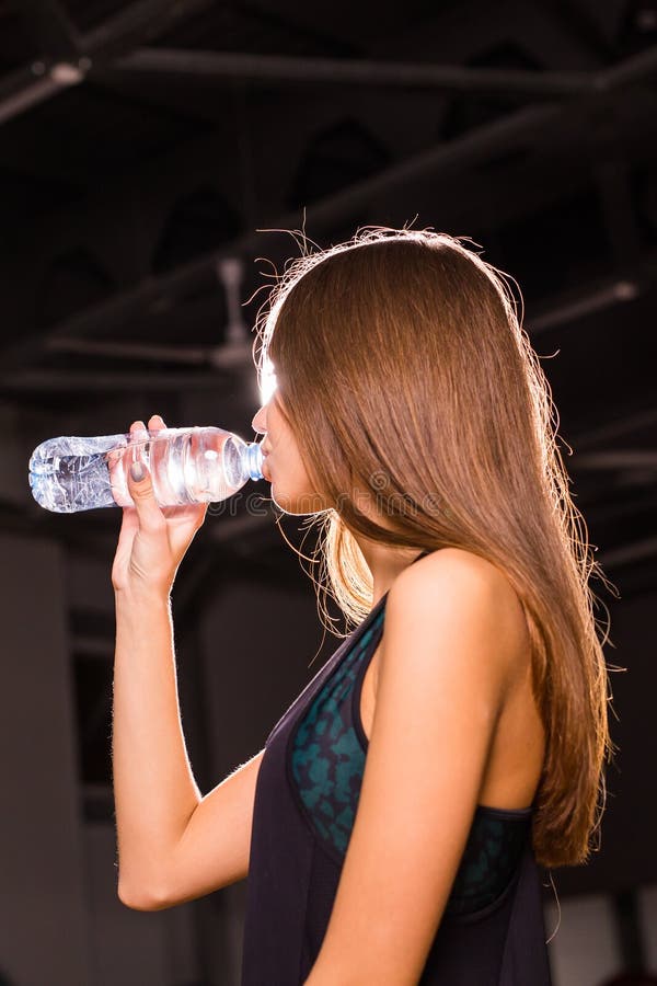 Água potável da jovem mulher da aptidão no gym Mulher muscular que toma a ruptura após o exercício imagem de stock Água potável da jovem mulher da aptidão no gym Mulher muscular que toma a ruptura após o exercício imagem de stock