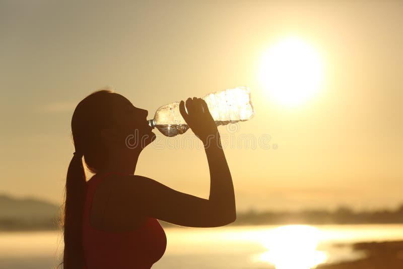 Água potável da silhueta da mulher da aptidão de uma garrafa imagens de stock Água potável da silhueta da mulher da aptidão de uma garrafa imagens de stock