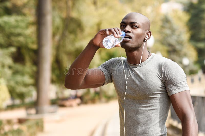 Água potável nova do homem negro antes de correr no backgroun urbano imagem de stock Água potável nova do homem negro antes de correr no backgroun urbano imagem de stock