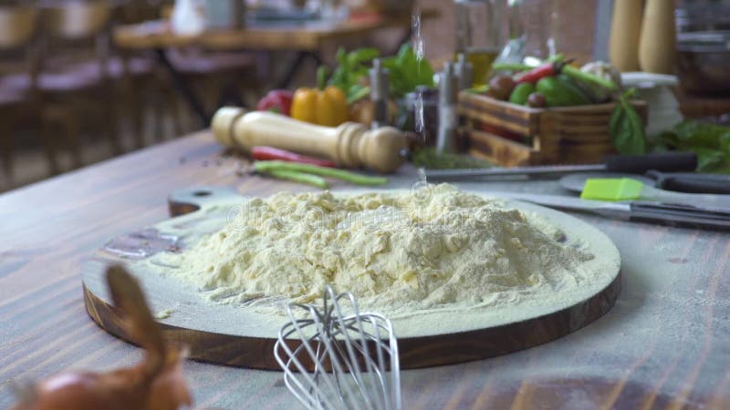 Água que derrama na farinha para a massa da preparação no movimento lento da cozinha da padaria Processe a fatura da massa para a