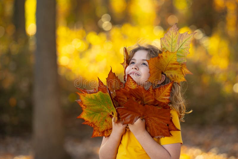 Ánimo otoñal para los niños. Niño pequeño en el retrato al aire libre de hojas anaranjadas de otoño. Niños divertidos con hojas de foto de archivo libre de regalías