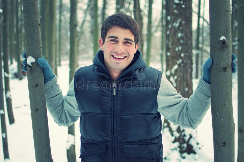 Árboles hermosos sonrientes de la explotación agrícola del hombre joven foto de archivo libre de regalías Árboles hermosos sonrientes de la explotación agrícola del hombre joven foto de archivo libre de regalías