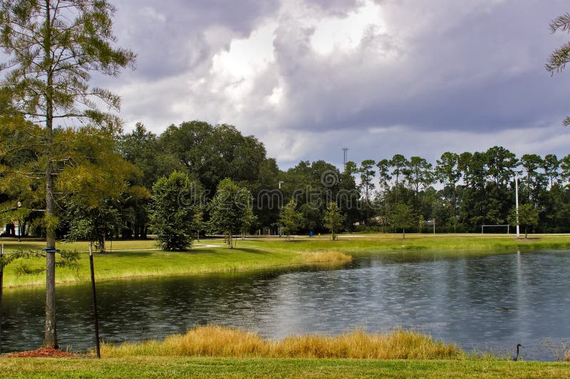 Park area with rain drops on pond and dramatic clouds in the sky. Park area with rain drops on pond and dramatic clouds in the sky.