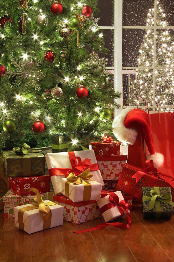 Árvore de Natal brilhantemente iluminada com lotes dos presentes