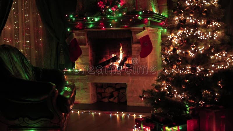 Árvore de Natal decorada no interior da sala com lareira, poltrona, janela