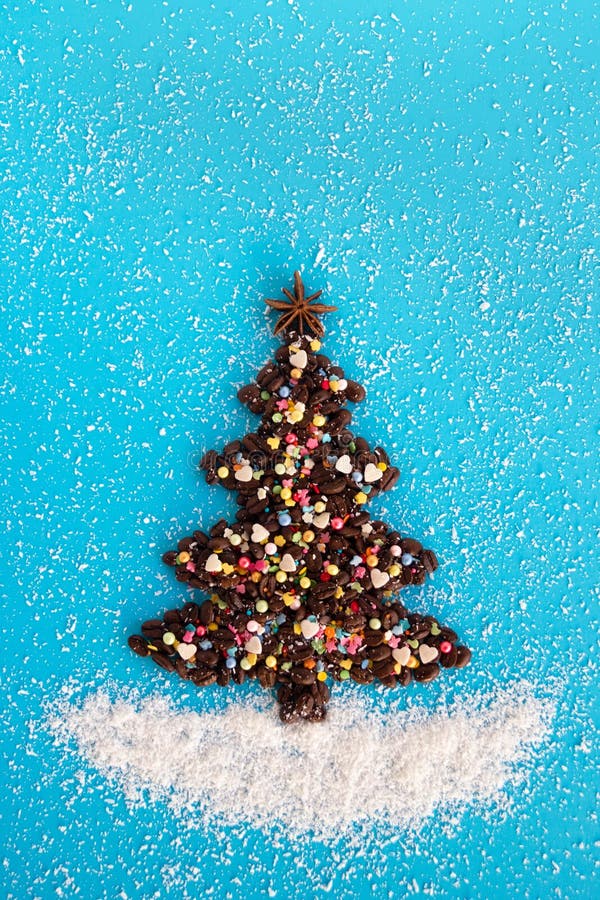 Árvore de Natal feita dos feijões de café e de polvilhar decorado, culinário e de microplaquetas do coco em um fundo azul, vista foto de stock Árvore de Natal feita dos feijões de café e de polvilhar decorado, culinário e de microplaquetas do coco em um fundo azul, vista foto de stock