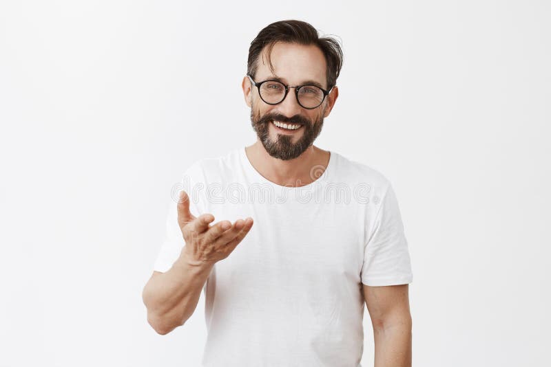 Ägna allt till dig Charmig tacksam europeisk man med skägget och stilfull frisyr i exponeringsglas som pekar med arkivfoto Ägna allt till dig Charmig tacksam europeisk man med skägget och stilfull frisyr i exponeringsglas som pekar med arkivfoto