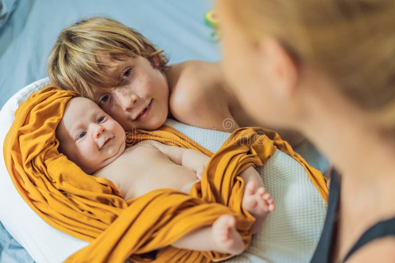Äldre bror kramar hans nyfödda syskon. Heartwarming Familjeögonblick kärlek och koppling mellan syskon. Barn royaltyfria bilder