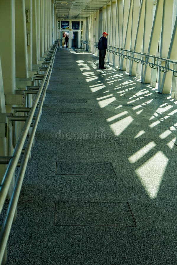 Roanoke, VA – December 18th: Elderly gentleman wearing a red hat walking across a footbridge over Norfolk & Southern rail yard located in Roanoke, Virginia, USA on December 18th, 2018. Roanoke, VA – December 18th: Elderly gentleman wearing a red hat walking across a footbridge over Norfolk & Southern rail yard located in Roanoke, Virginia, USA on December 18th, 2018.