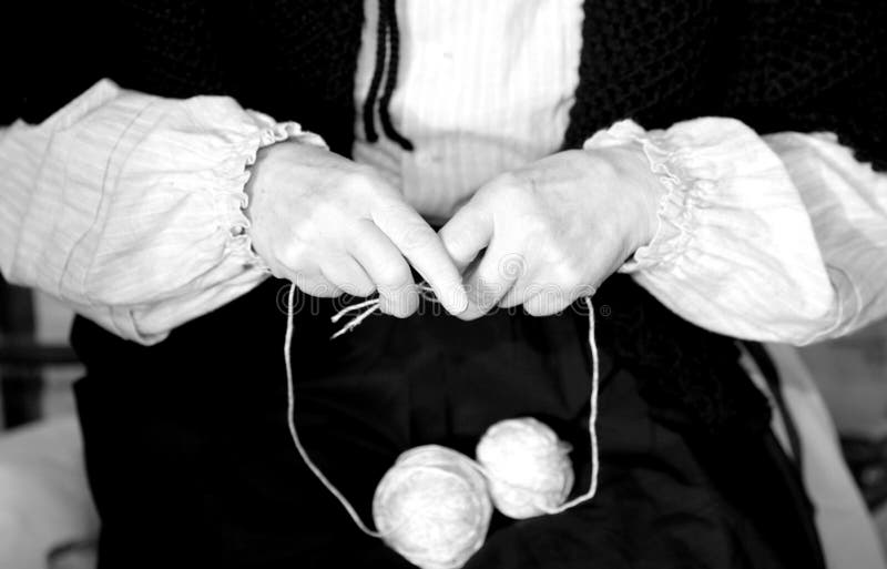 hands of elderly woman while knitting wool with two woolen threads and white and black effect. hands of elderly woman while knitting wool with two woolen threads and white and black effect