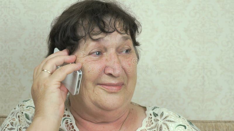 Äldre kvinna som hemma talar på telefonen