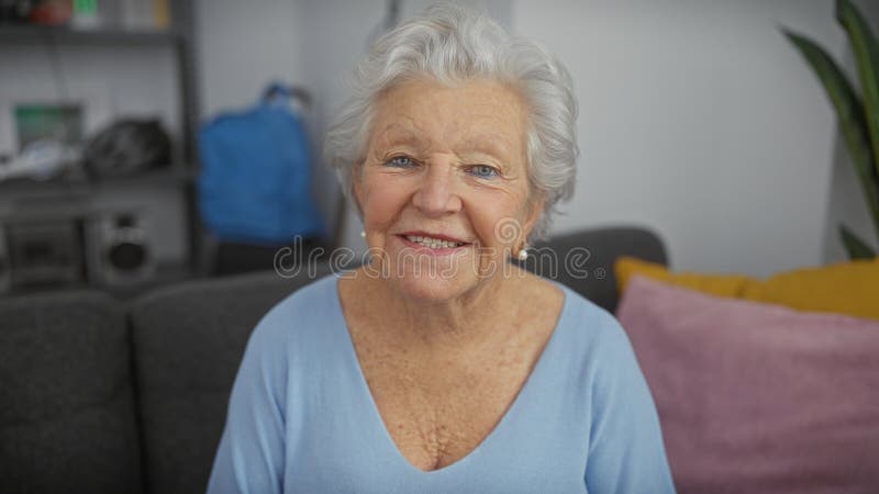 Äldre kvinnor som leker inomhus med grått hår med blå topp i ett modernt vardagsrum royaltyfri fotografi