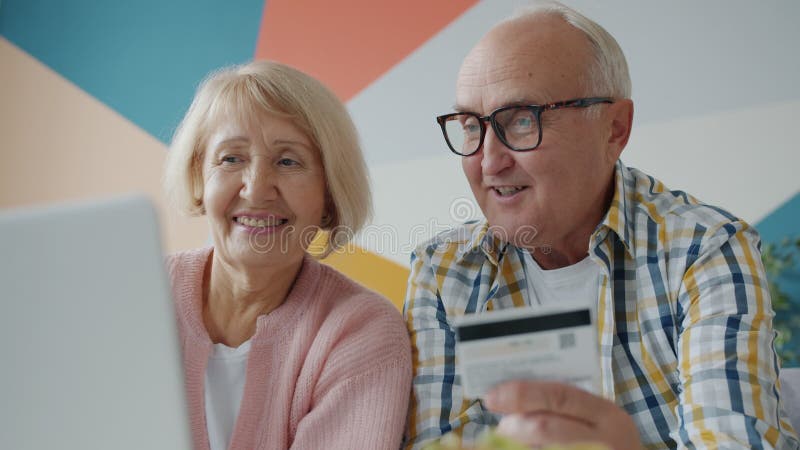 Äldre par som gör betalningar online med kreditkortsshopping