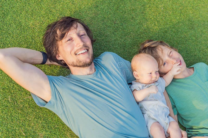 Äldre son och nyfödd barn på en ängsmark i parken. Familjeutgifter av hög kvalitet tillsammans i naturen. Parenthood royaltyfria foton