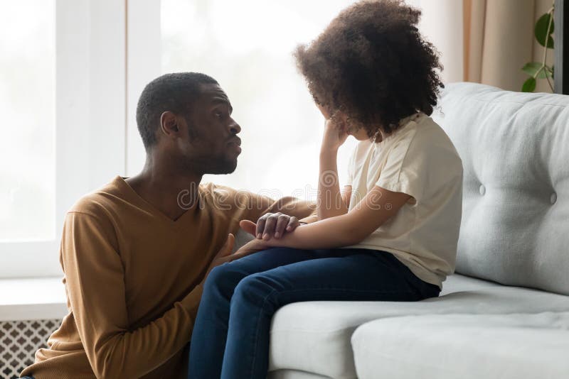 Loving african american dad comforting crying sad kid daughter holding hand supporting little stressed school girl in tears, black father consoling talking to upset child giving empathy protection. Loving african american dad comforting crying sad kid daughter holding hand supporting little stressed school girl in tears, black father consoling talking to upset child giving empathy protection