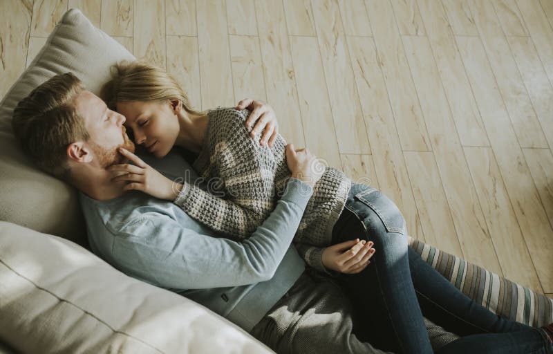 Älska par som ner ligger på soffan i rummet royaltyfria bilder Älska par som ner ligger på soffan i rummet royaltyfria bilder