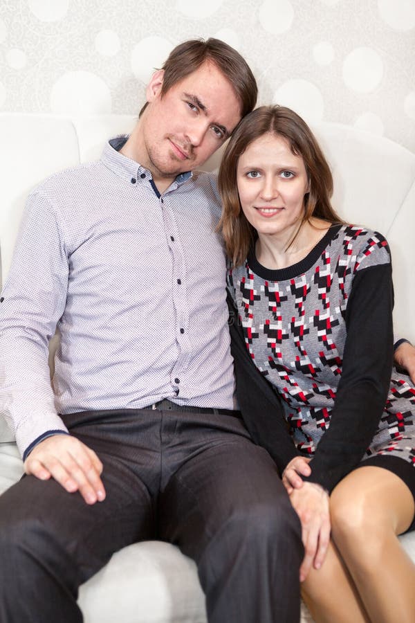 Älska ungt Caucasian parsammanträde på soffan tillsammans royaltyfria bilder Älska ungt Caucasian parsammanträde på soffan tillsammans royaltyfria bilder