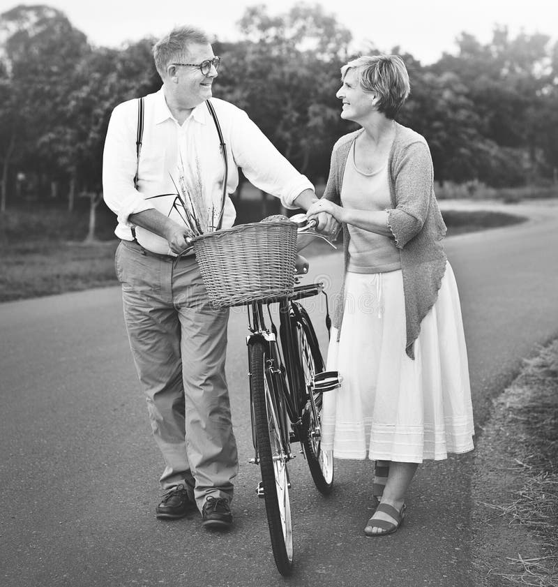 Älskvärt mogna par med en cykel arkivfoton Älskvärt mogna par med en cykel arkivfoton