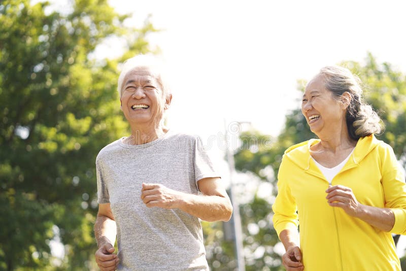 Happy asian senior couple running exercising outdoors in park. Happy asian senior couple running exercising outdoors in park