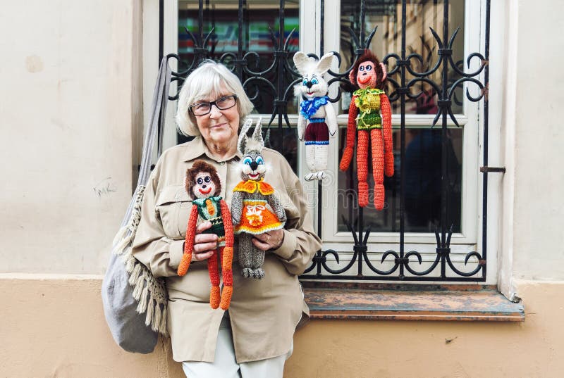 Ältere Dame, die handgemachte gestrickte Spielwaren auf der Straße verkauft stockbilder Ältere Dame, die handgemachte gestrickte Spielwaren auf der Straße verkauft stockbilder
