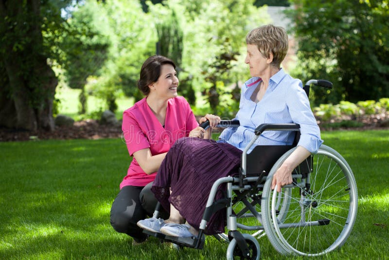 Ältere Frau auf Rollstuhl mit mitfühlender Pflegekraft