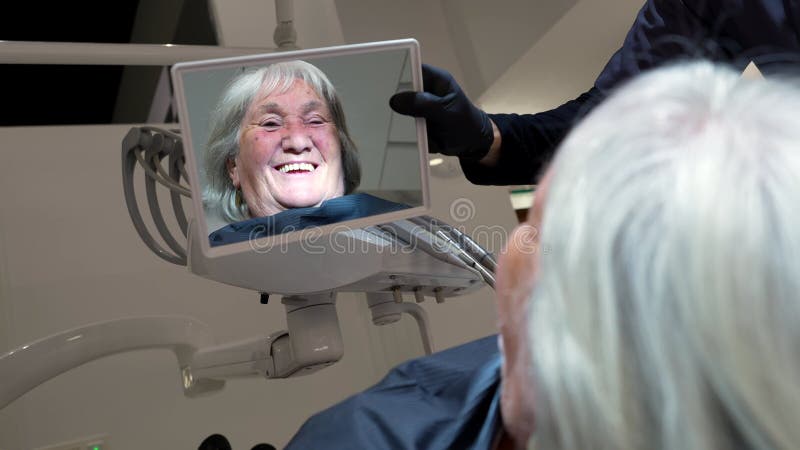 Ältere Frau bewundert ihr neues Lächeln nach Zahnbehandlung stock video