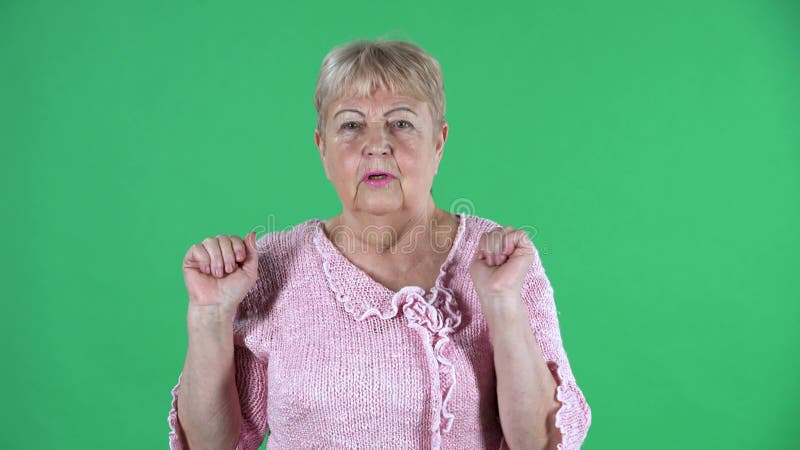 ältere Frau des Portraits, die Verwirrung mit Bestürzung sieht. graue behaarte Großmutter mit dem kurzen Haar in einer rosa Pullov