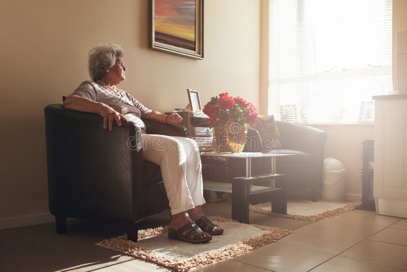 Ältere Frau, die allein zu Hause auf einem Stuhl sitzt