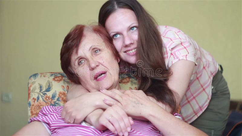 Ältere Frau, die im Stuhl umarmt ihr Mädchen sitzt
