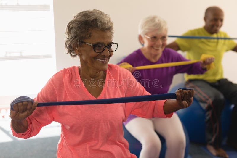 Happy senior women exercising with resistance band in fitness studio. Happy senior women exercising with resistance band in fitness studio