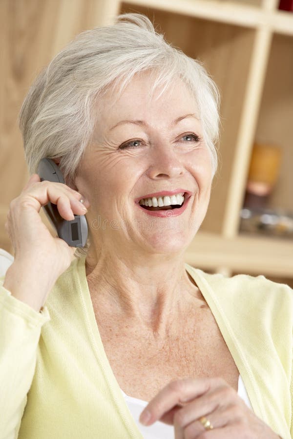 Ältere Frau, die zu Hause Telefon verwendet lizenzfreie stockfotos Ältere Frau, die zu Hause Telefon verwendet lizenzfreie stockfotos