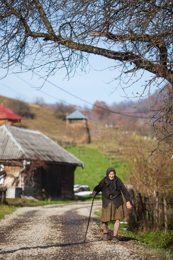 Ältere Frau geht hinunter eine Straße in einem Dorf lizenzfreies stockbild Ältere Frau geht hinunter eine Straße in einem Dorf lizenzfreies stockbild