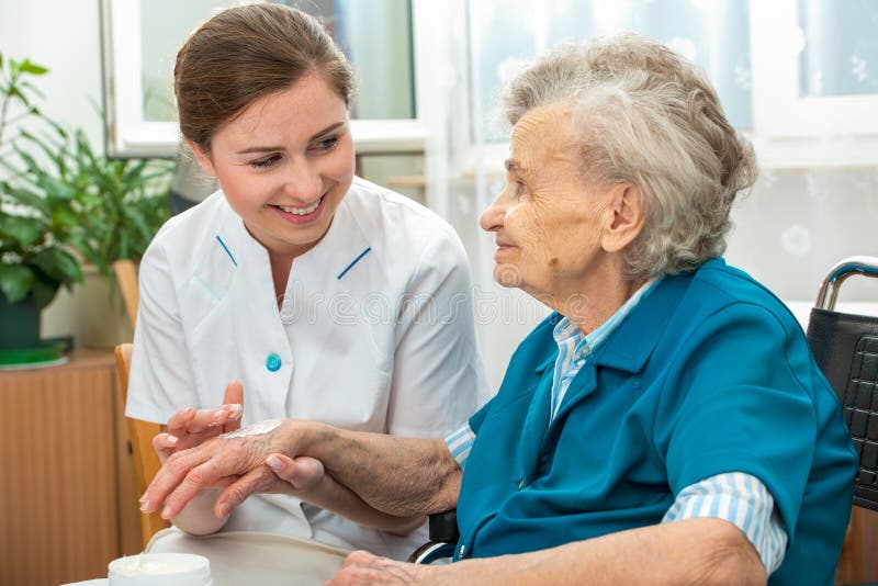 Ältere Frau wird von der Krankenschwester zu Hause unterstützt stockbilder