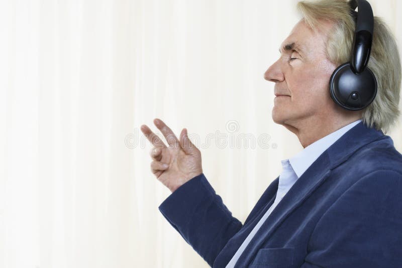 Side view of a senior businessman enjoying music with headphones. Side view of a senior businessman enjoying music with headphones