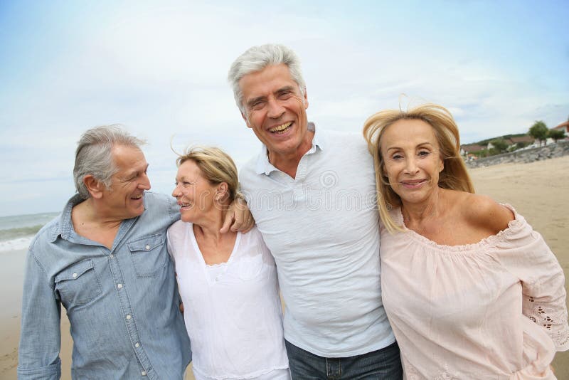 Ältere glückliche Menschen, die auf sandigen Strand gehen stockbild Ältere glückliche Menschen, die auf sandigen Strand gehen stockbild