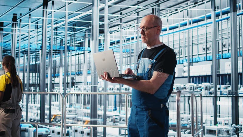 Ältere Ingenieure verwenden Laptops in intelligenten Fabriken, um automatisierte Systeme zu testen stock video