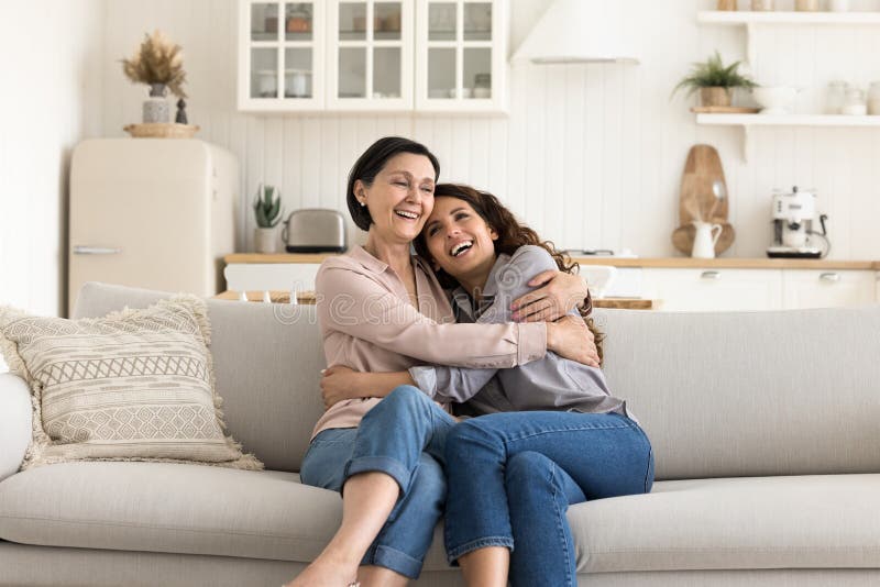 Ältere Mama kuscheln mit erwachsener Tochter auf Couch zu Hause lizenzfreies stockbild